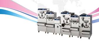 A row of stainless‑steel industrial machines arranged side by side against a beige background with pink and blue graphic lines.