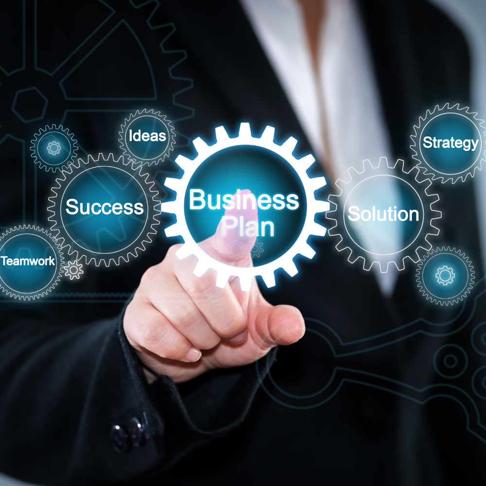 A person in business attire touches an illuminated gear labeled ‘Business Plan’, surrounded by additional gears with terms such as strategy, success, ideas and solution.