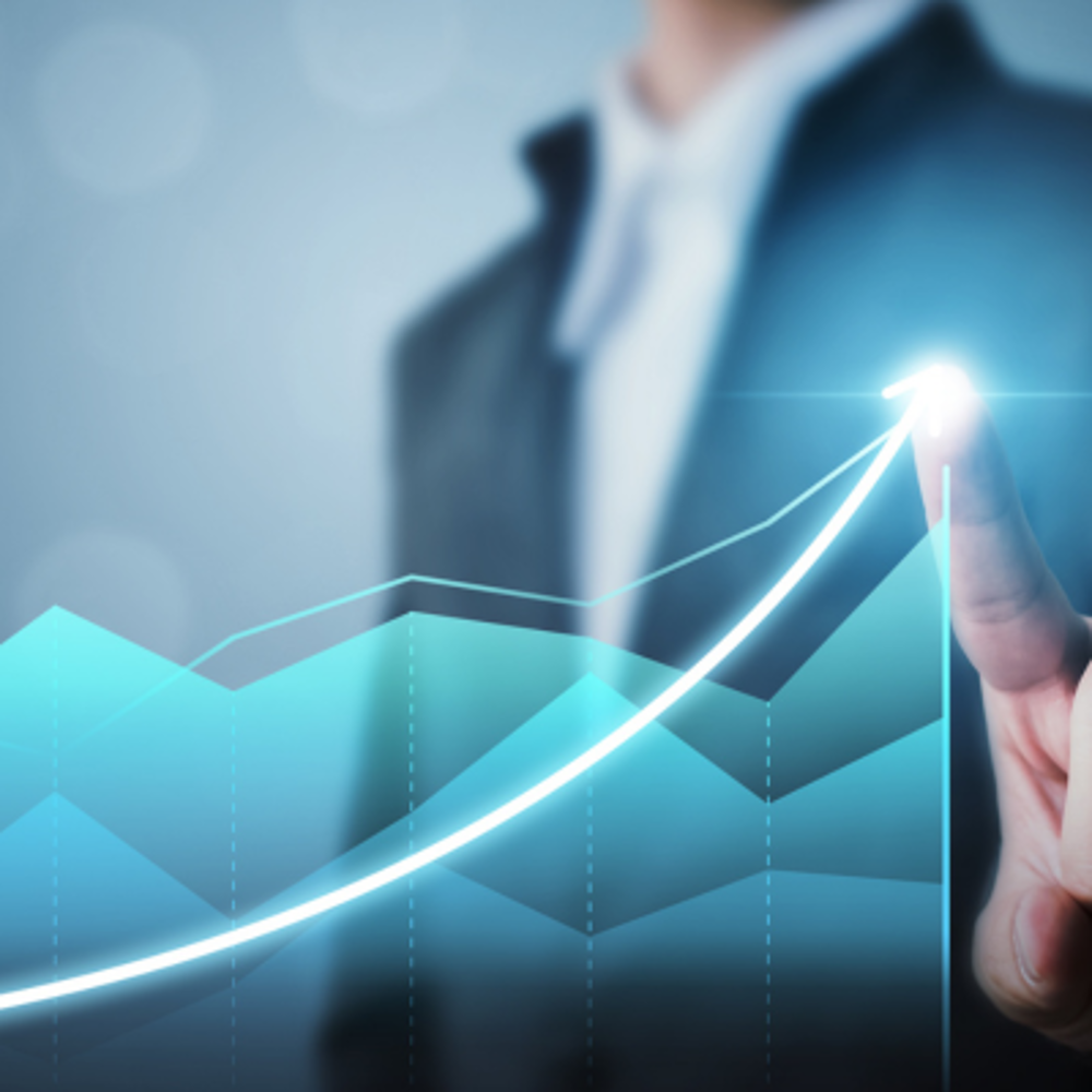 A person in a business suit touches a glowing point on a chart showing an upward growth curve. A layered line graph with marked trends appears in the background.
