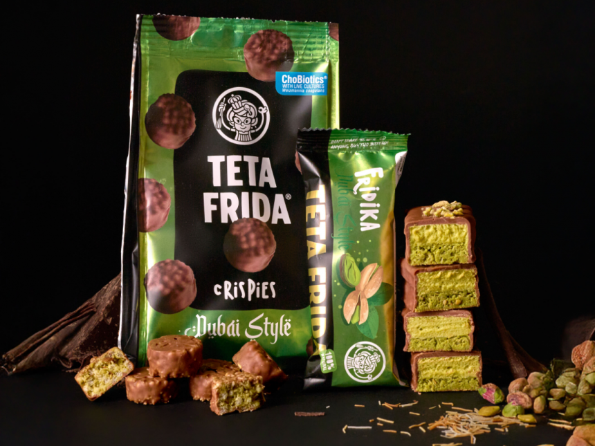 Packages of Teta Frida chocolate snacks and a green ReMix bar are displayed beside stacked pistachio pieces on a dark surface.